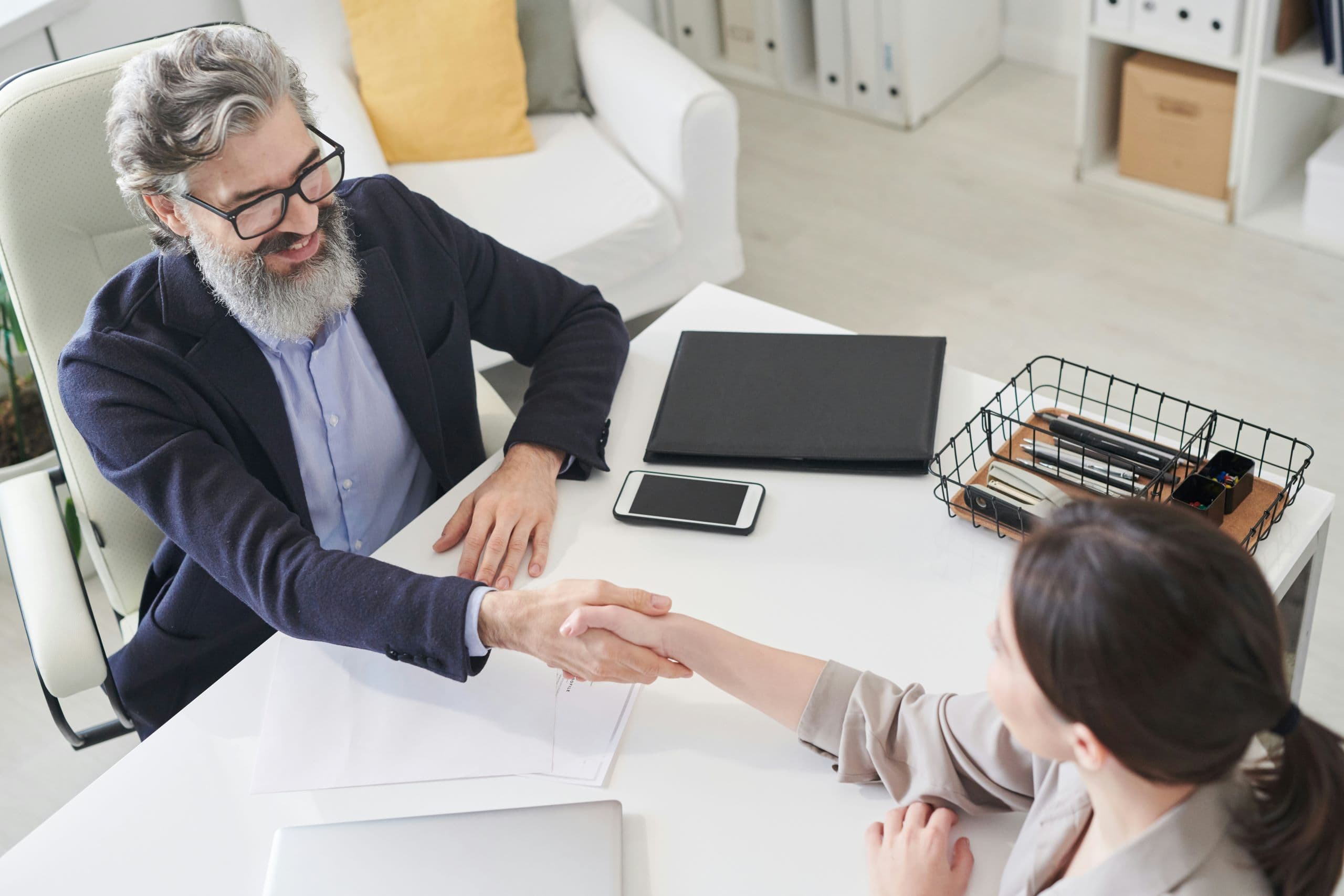 A man shaking hands with a woman at a desk