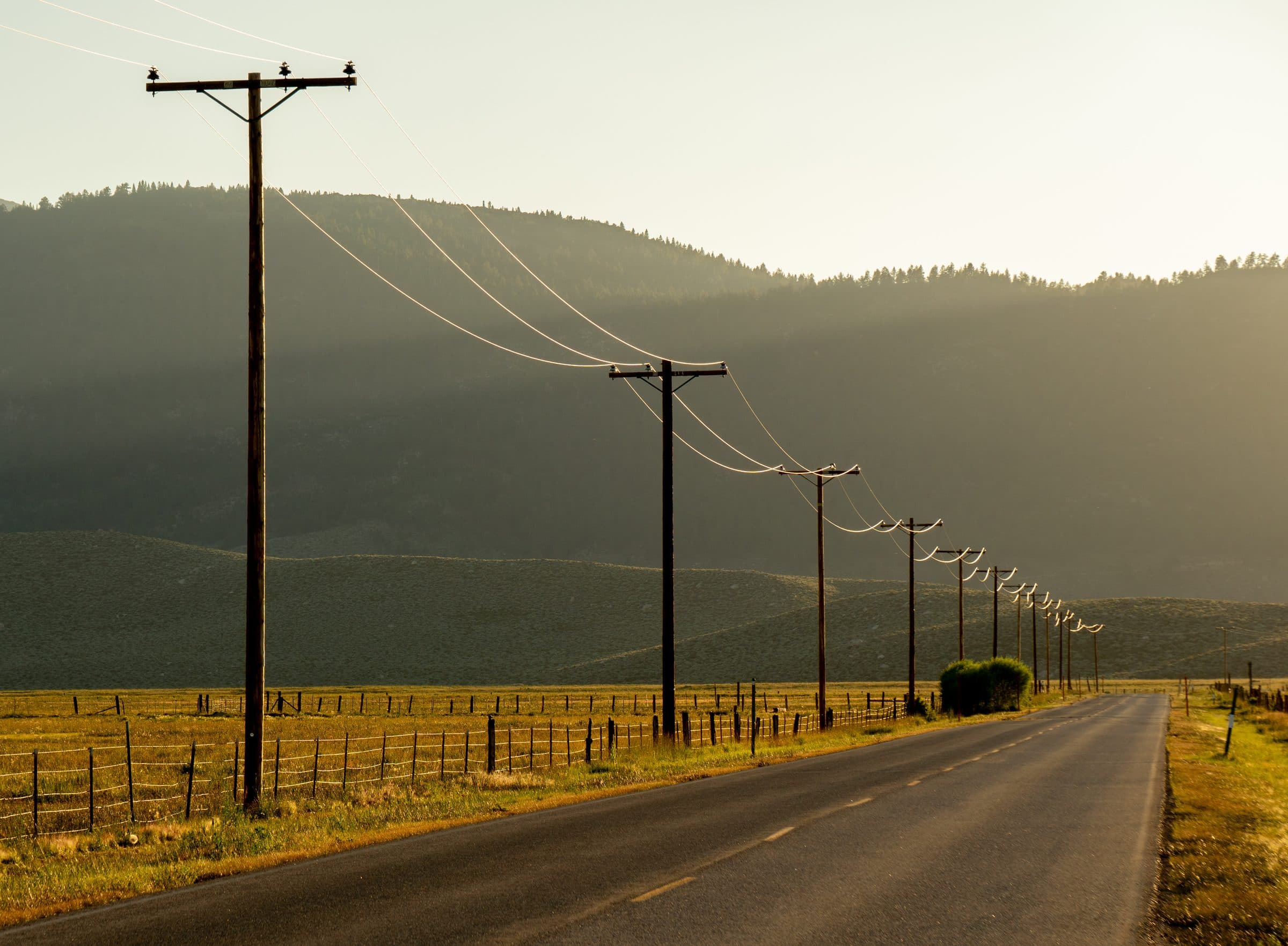 A rural highway running toward the hills at golden hour